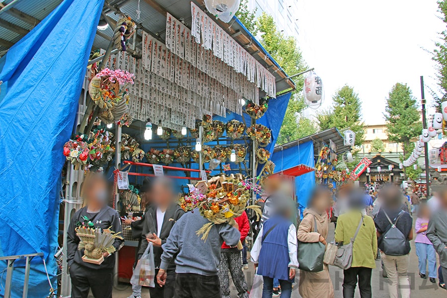 熊手の露店と熊手を持つ参拝者の往来で賑わう境内の様子