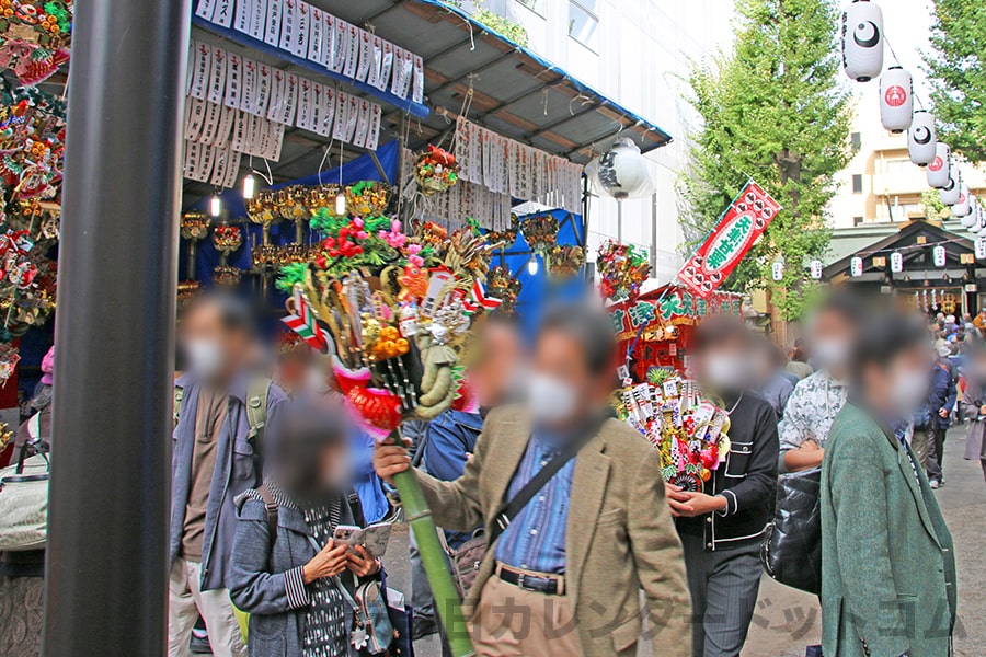 大きな熊手を担いで帰路につく参拝者たちの様子