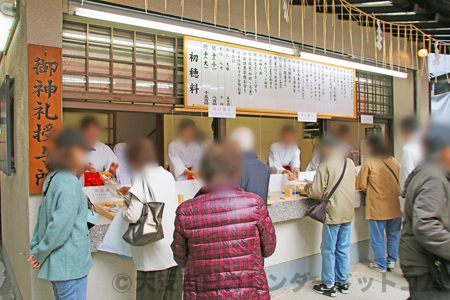 お参りの後、授与所にて熊手を授与してもらっている参拝者の様子